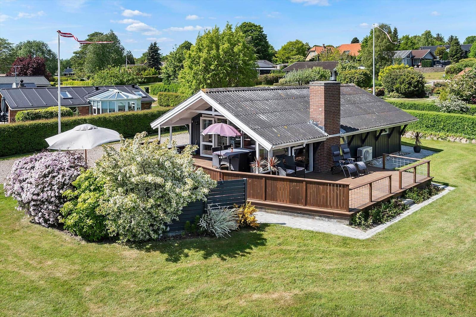 Haus mit Terrasse, Garten und Flagge. Grillplatz und Sitzgelegenheiten.