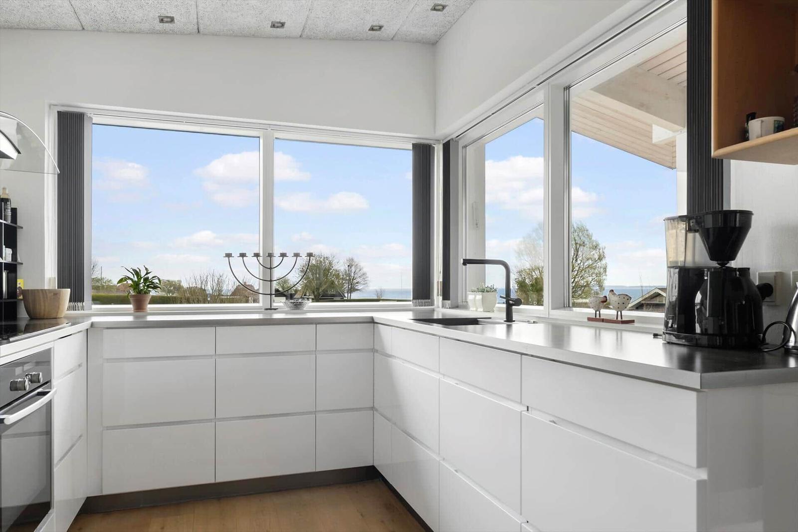 Kitchen with white cabinets and large window view of the sea