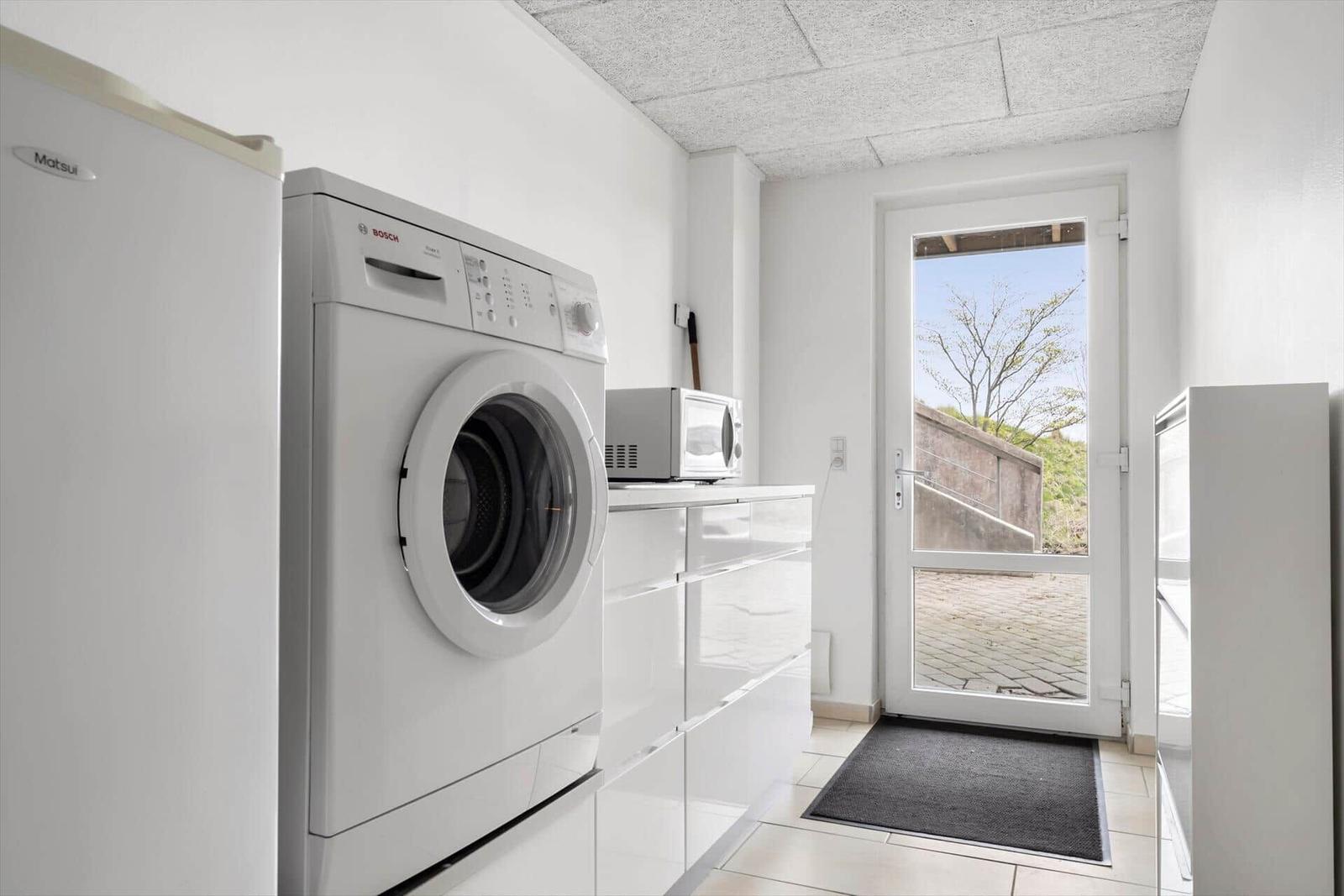 Apartment with washing machine, fridge, and microwave. Door leads outside.