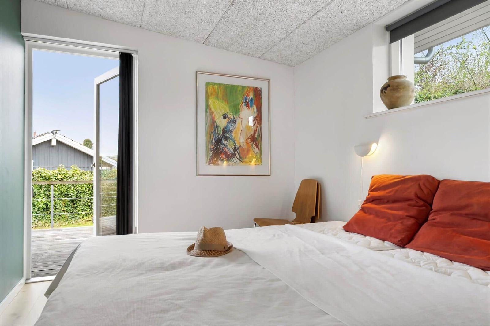 Bedroom with bed, wall art, and view to balcony.