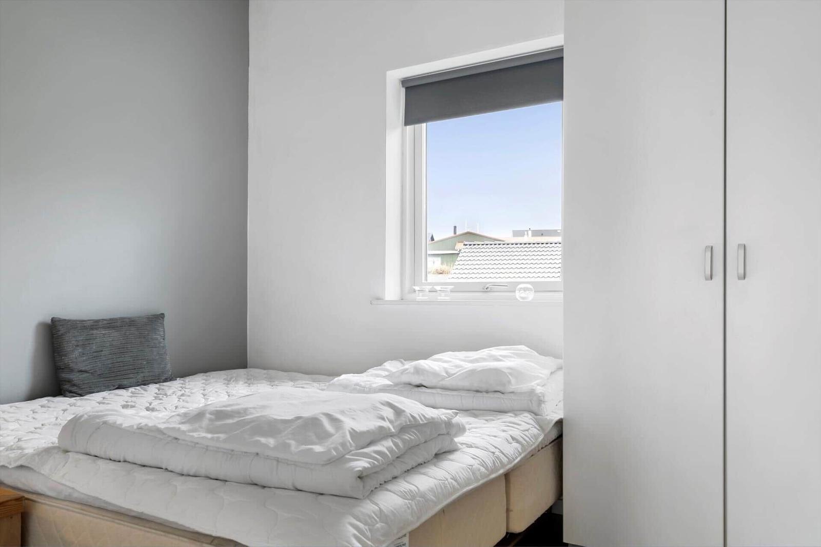 Bedroom with bed, window, and wardrobe.