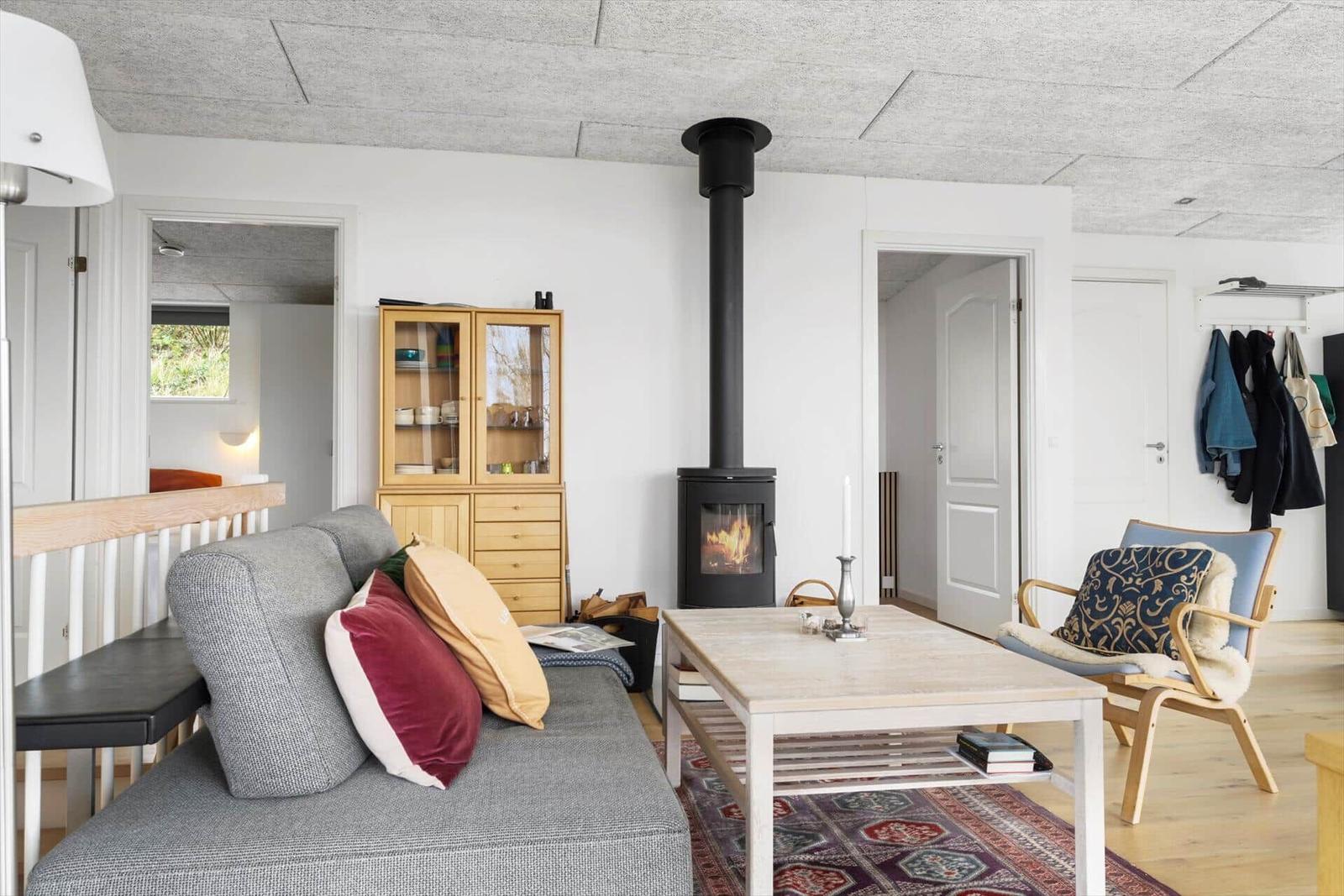 Living room with sofa, fireplace, and wooden table. White walls and wooden floor.