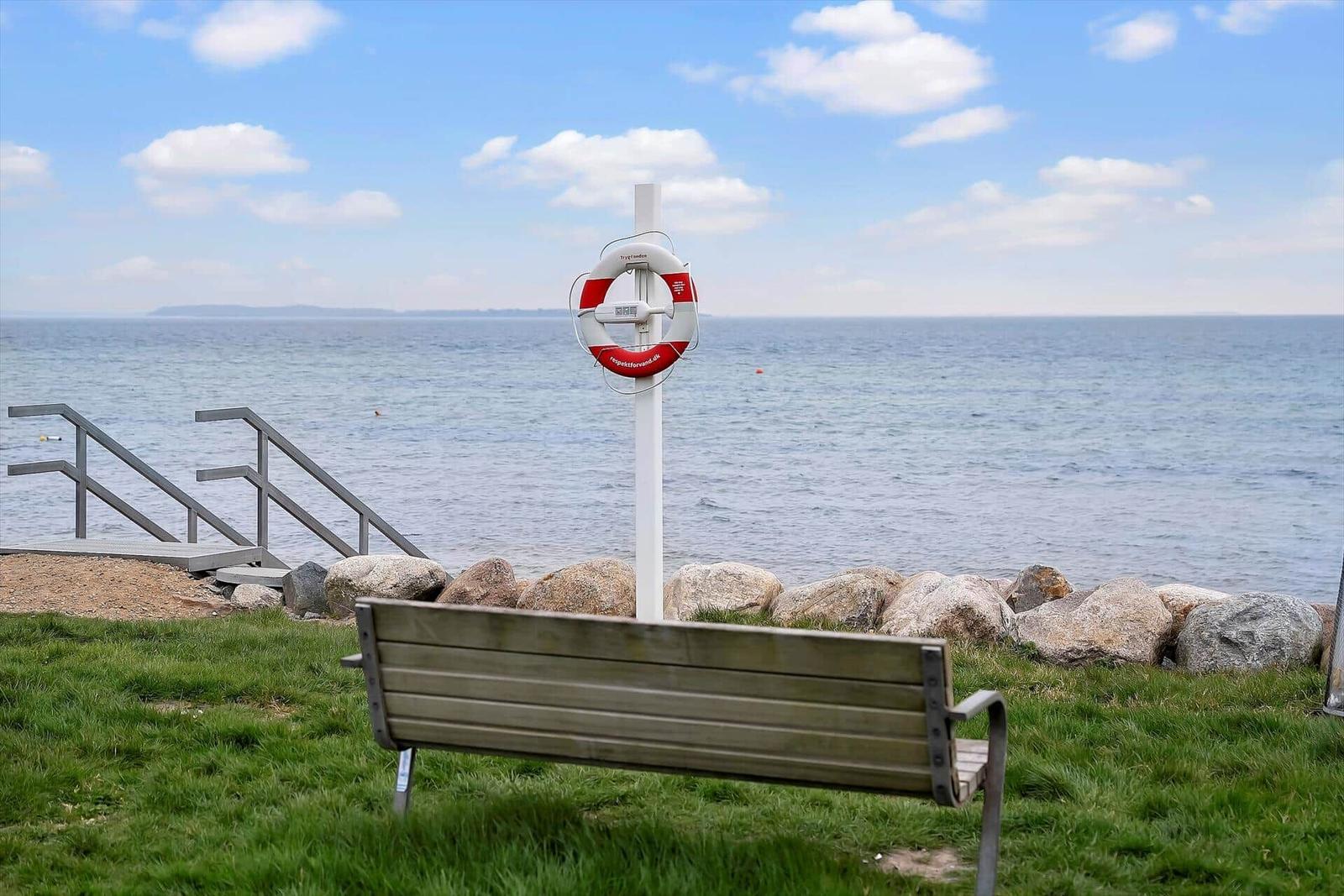 View of the sea with lifebuoy and bench in the foreground.
