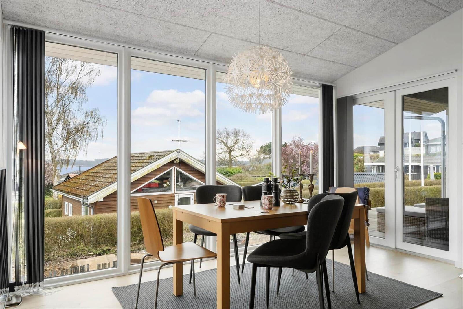 Dining room with table, chairs, and view of garden and house.