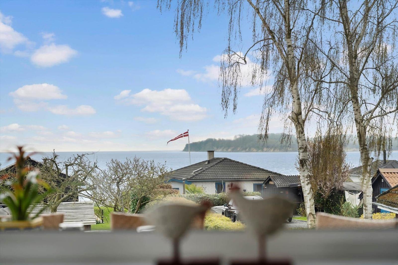View of the sea with trees and a house in the foreground.