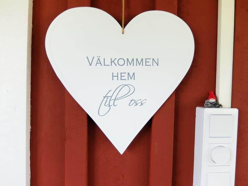 Herz mit Willkommensschild an roter Holzwand