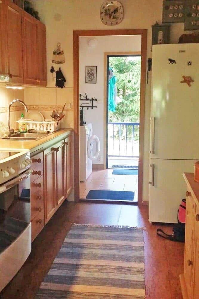 Küche mit Holzschränken, Kühlschrank und Blick auf Balkon.