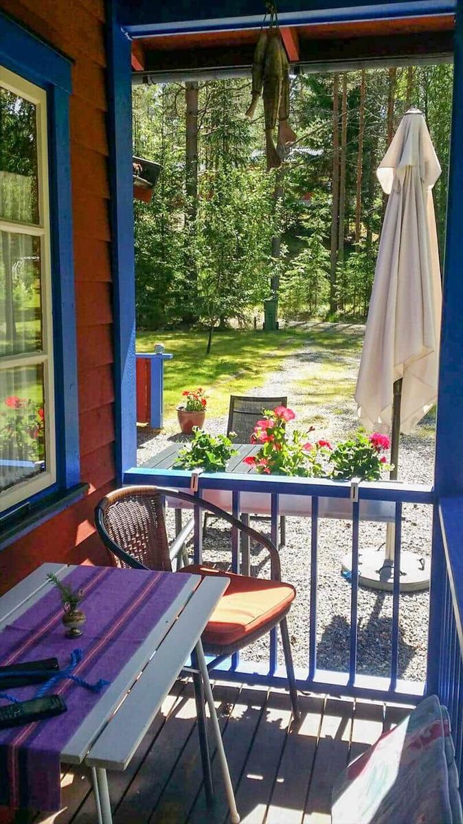 Terrasse mit Tisch, Stühlen und Sonnenschirm. Blick auf grünen Garten und Wald.
