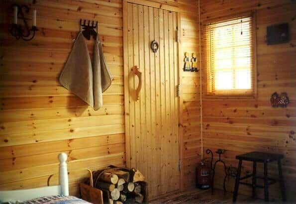 Holzvertäfelte Wand, Tür, Fenster mit Jalousie, Stuhl und Feuerholz