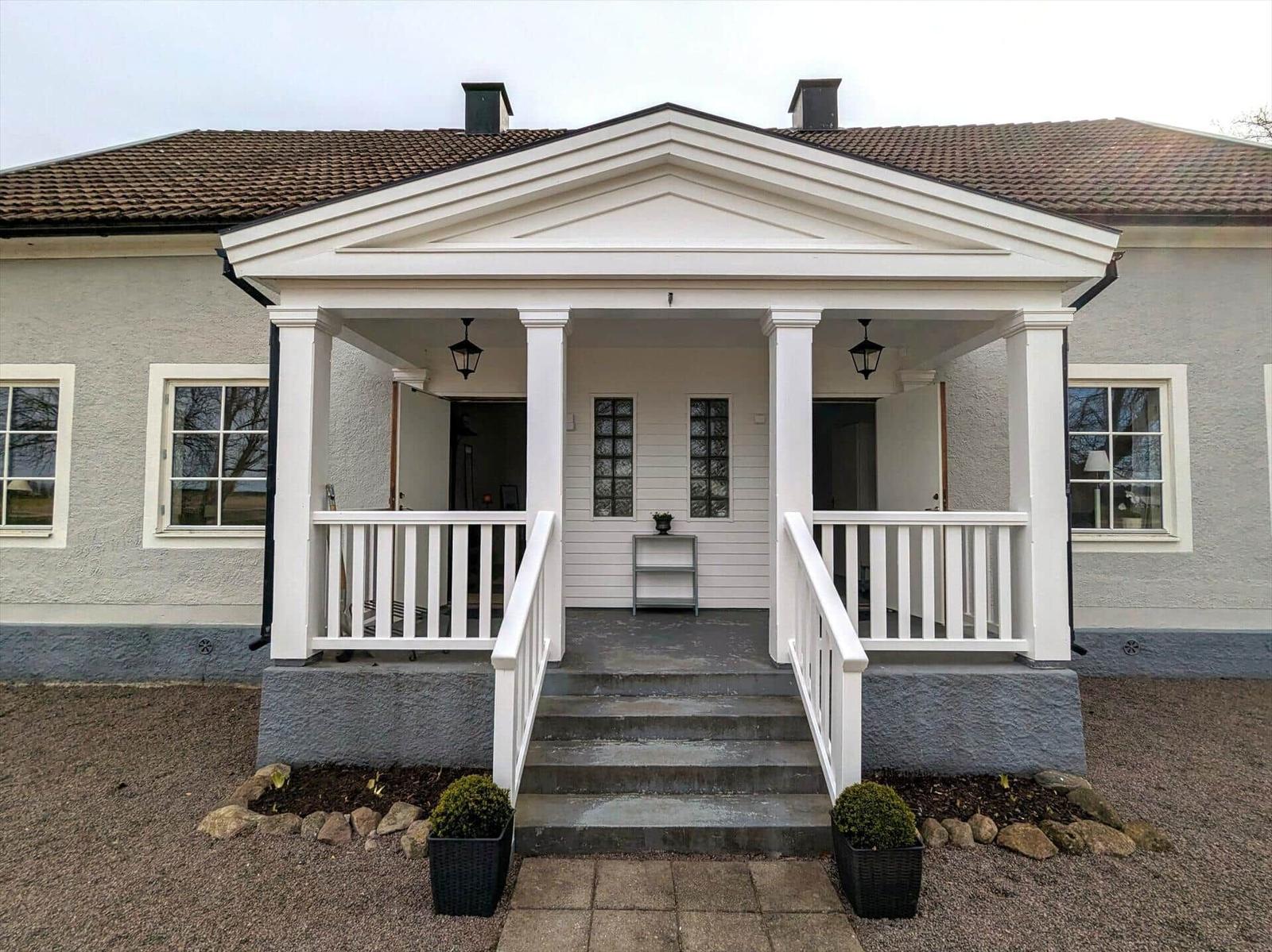 Haus mit weißem Vordach, Stufen und Pflanzen im Vorgarten.