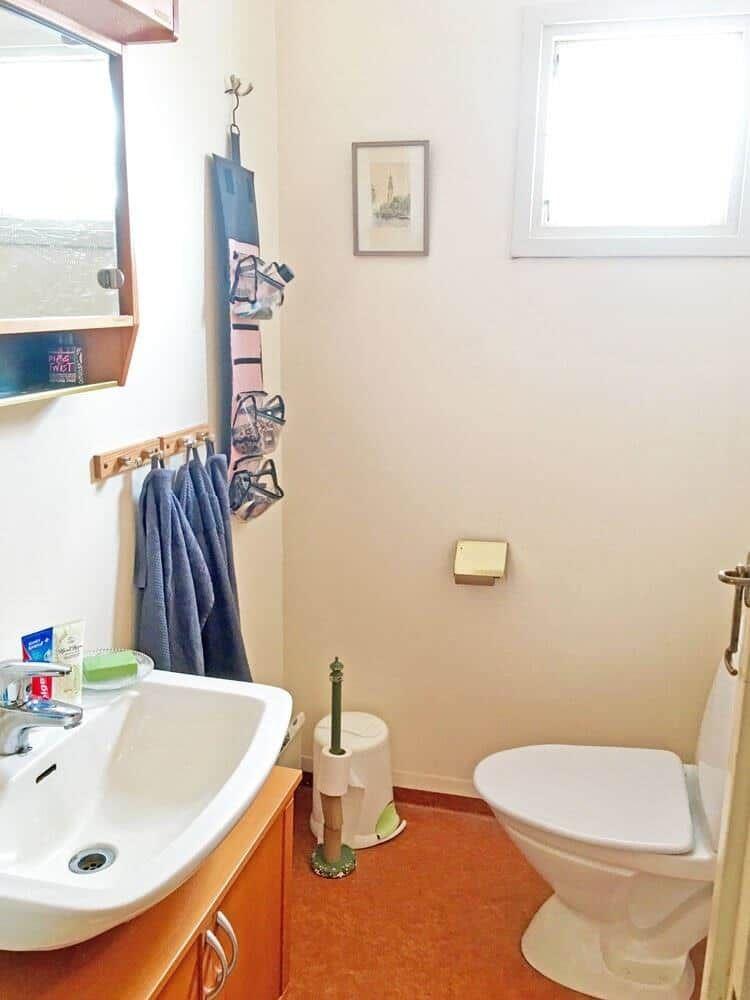 Badezimmer mit Waschbecken, Toilette und Fenster.