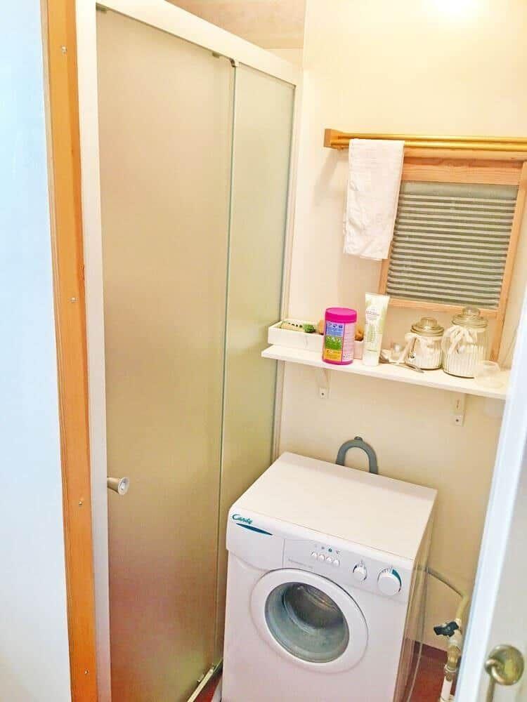 Waschmaschine in einem kleinen Raum mit Schiebetür und Regal.