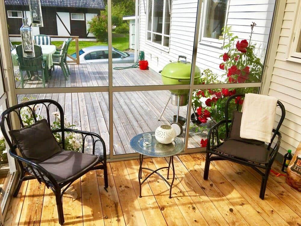 Terrasse mit zwei Stühlen und Tisch, Blick auf Grill und Blumen.