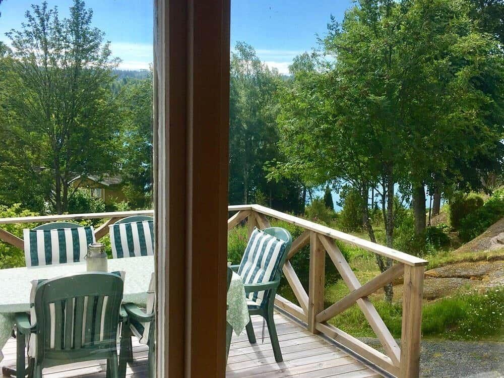 Terrasse mit Tisch und Stühlen, Blick auf Wald und Wasser