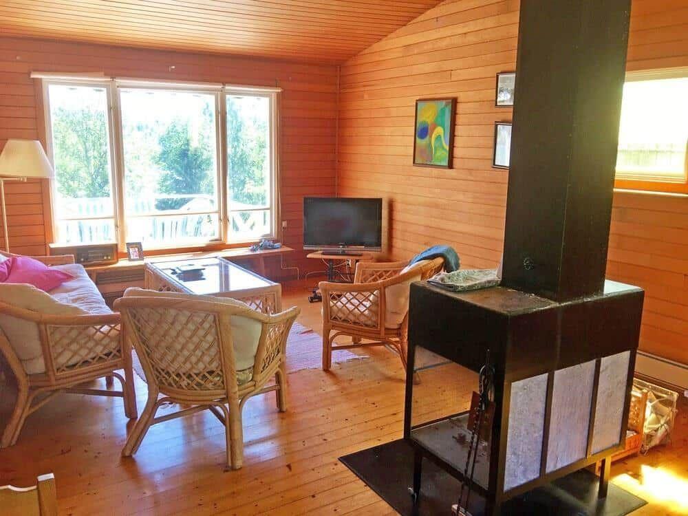 Wohnzimmer mit Holzwand, Kamin, TV und Sitzgelegenheiten.