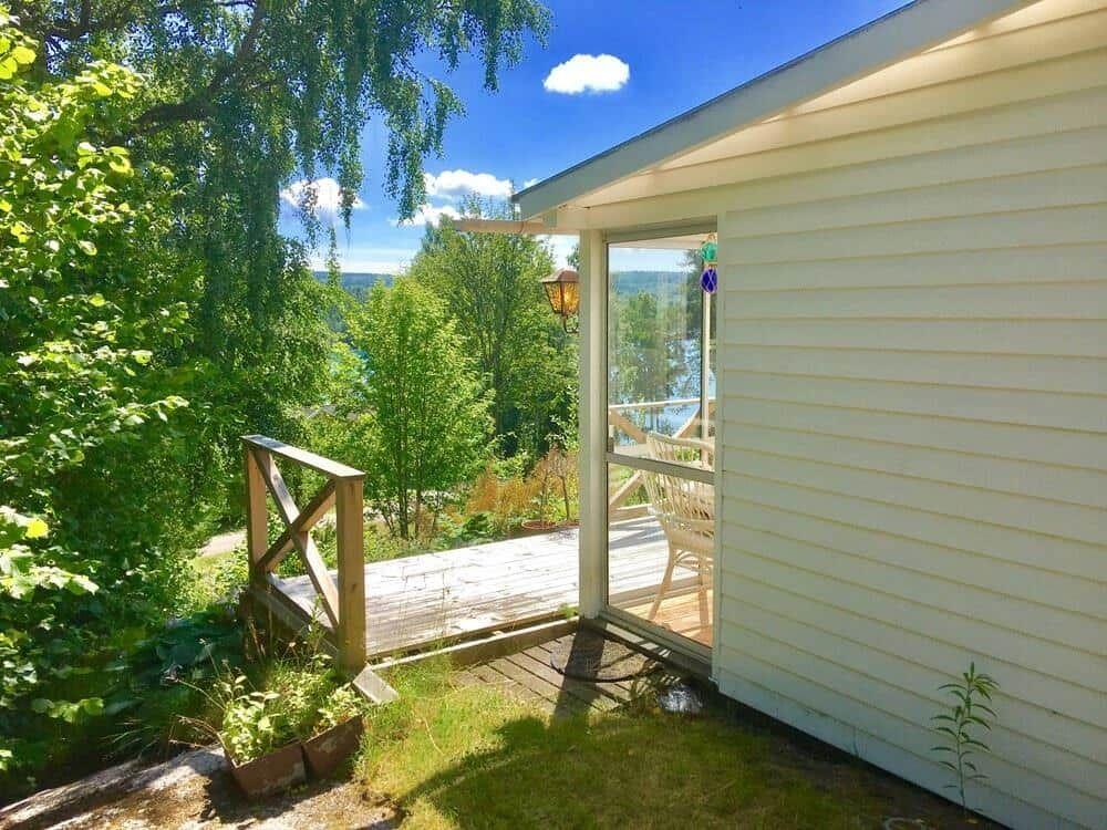Terrasse mit Blick auf Wald und See. Holzgeländer und Glastür.