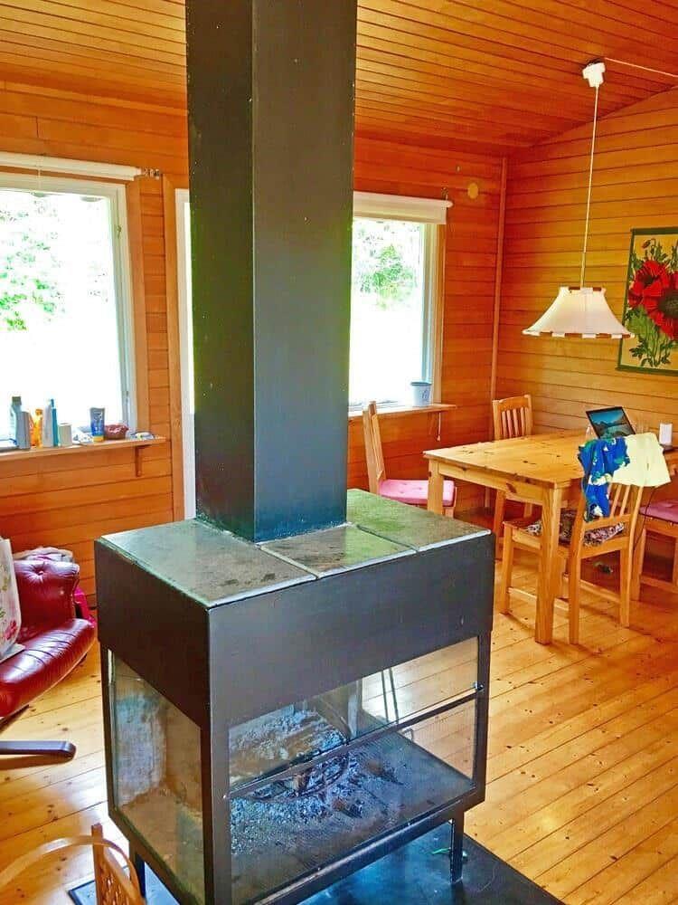 Holzvertäfelte Wohnung mit Kamin, Esstisch und Fenstern.