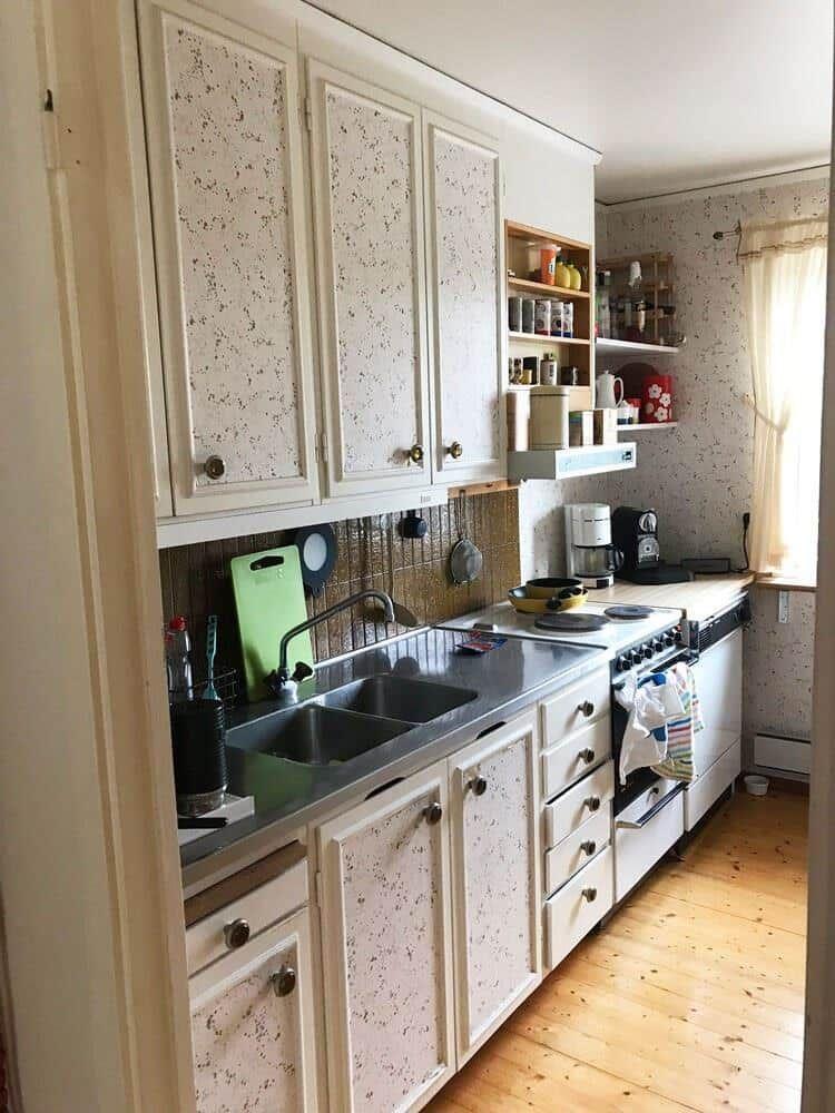 Küche mit weißen Schränken, Edelstahlspüle und Holzboden.