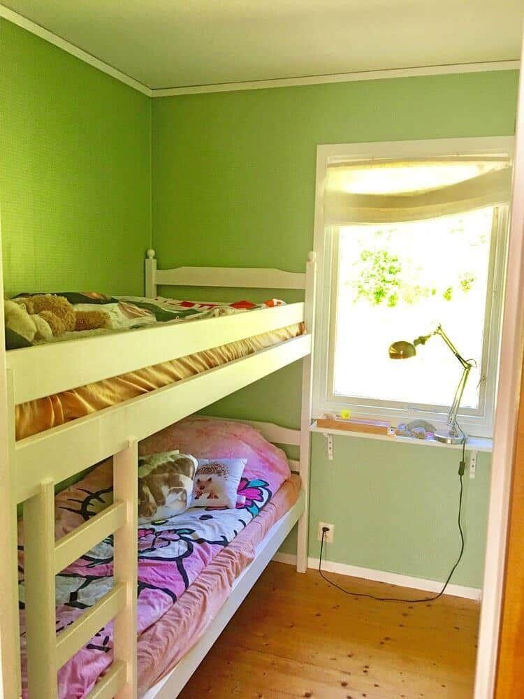 Zimmer mit Doppelstockbett, Fenster und Schreibtisch mit Lampe.