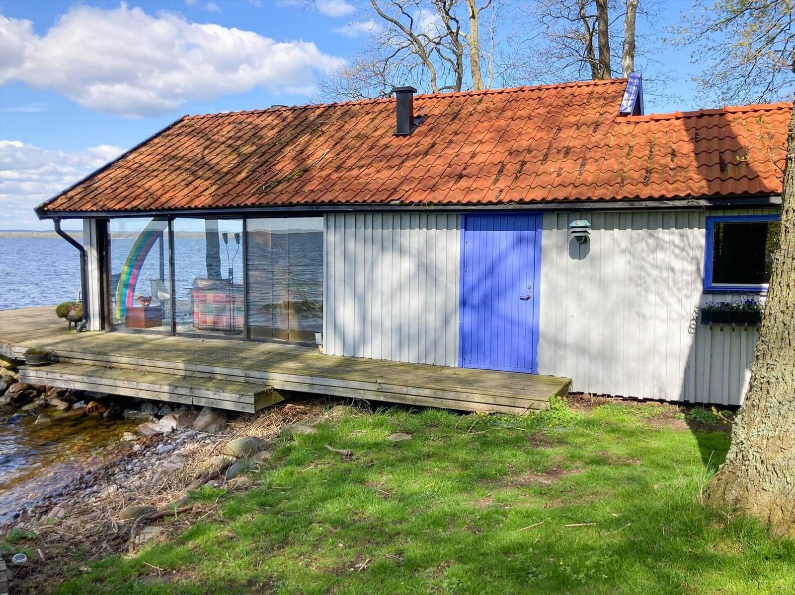 Haus mit rotem Dach und blauer Tür am Wasser