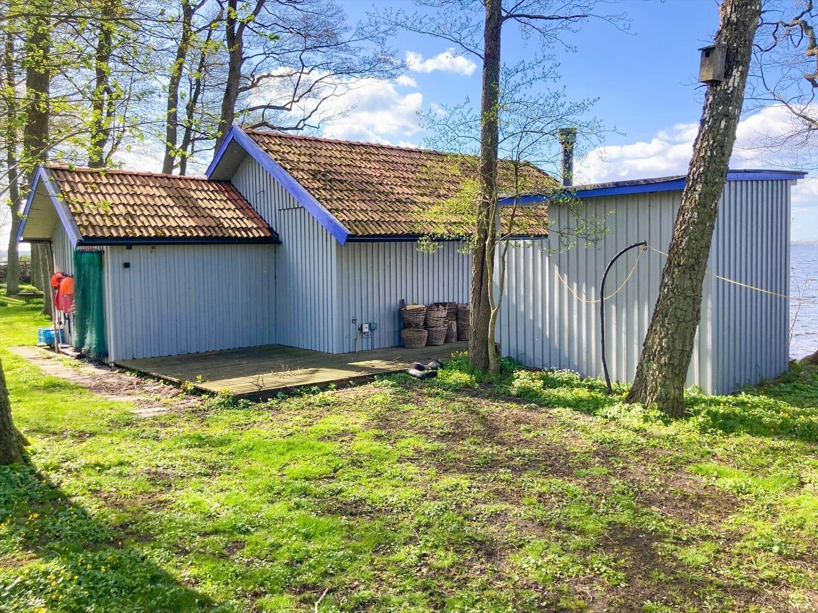 Haus mit Holzterrasse, umgeben von Bäumen und Grasflächen.