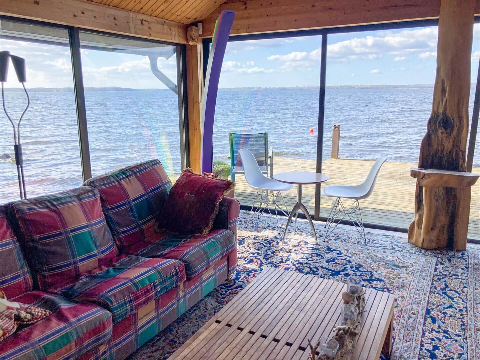 Wohnbereich mit Sofa, Tisch und Blick auf Wasser