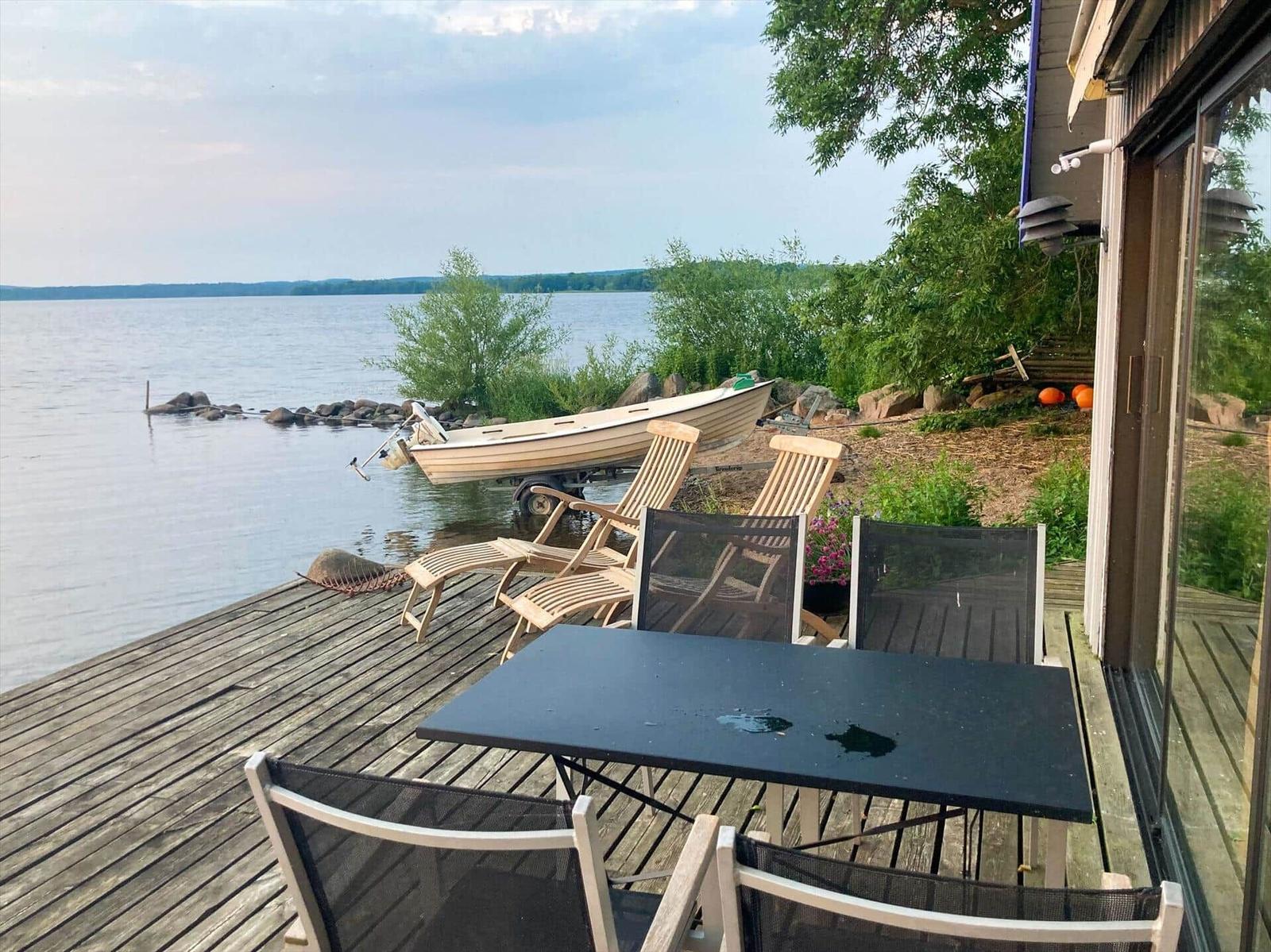 Terrasse mit Tisch und Stühlen am See mit Boot.