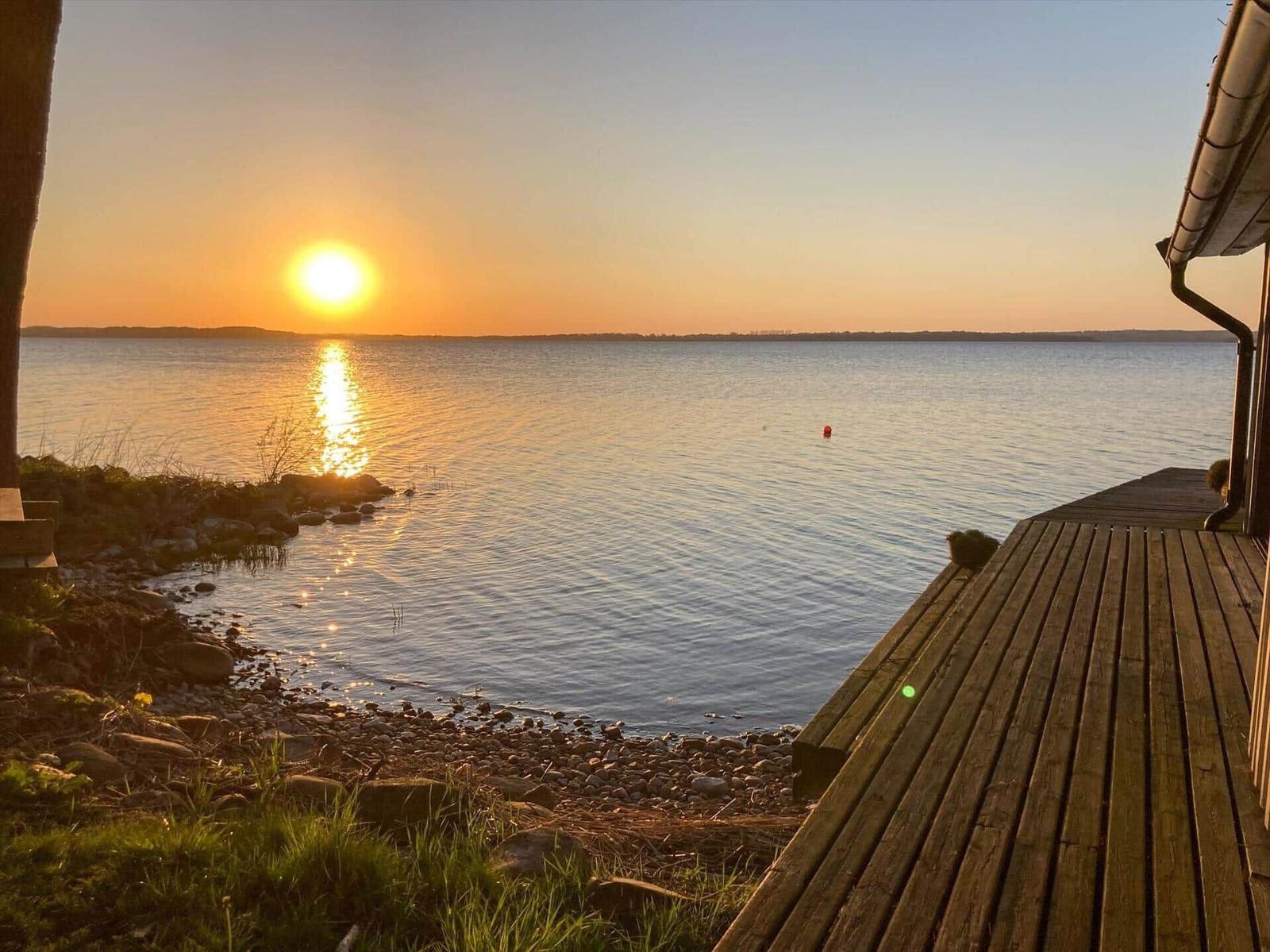 Sonnenuntergang über See mit Holzterrasse und Steilufer