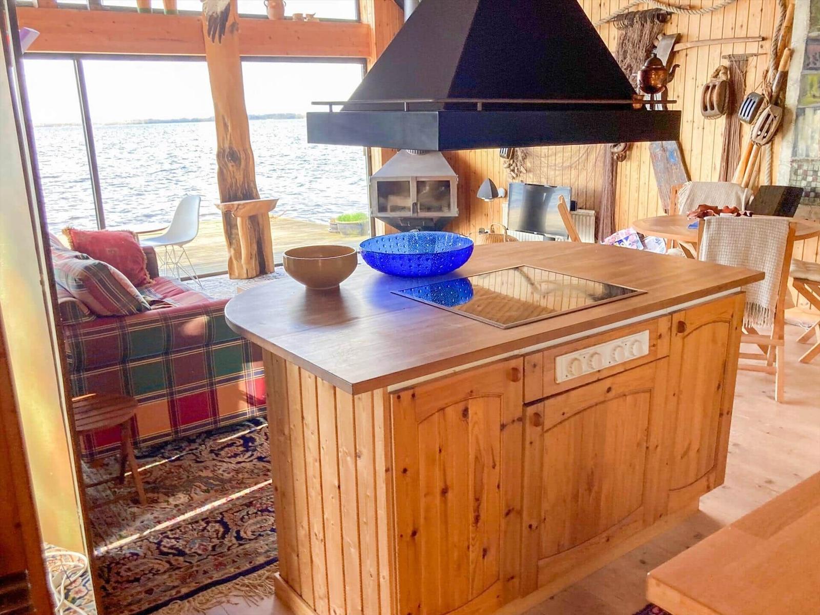 Küche mit Holzinsel, Blick auf Wasser, Sofa und Feuerkamin