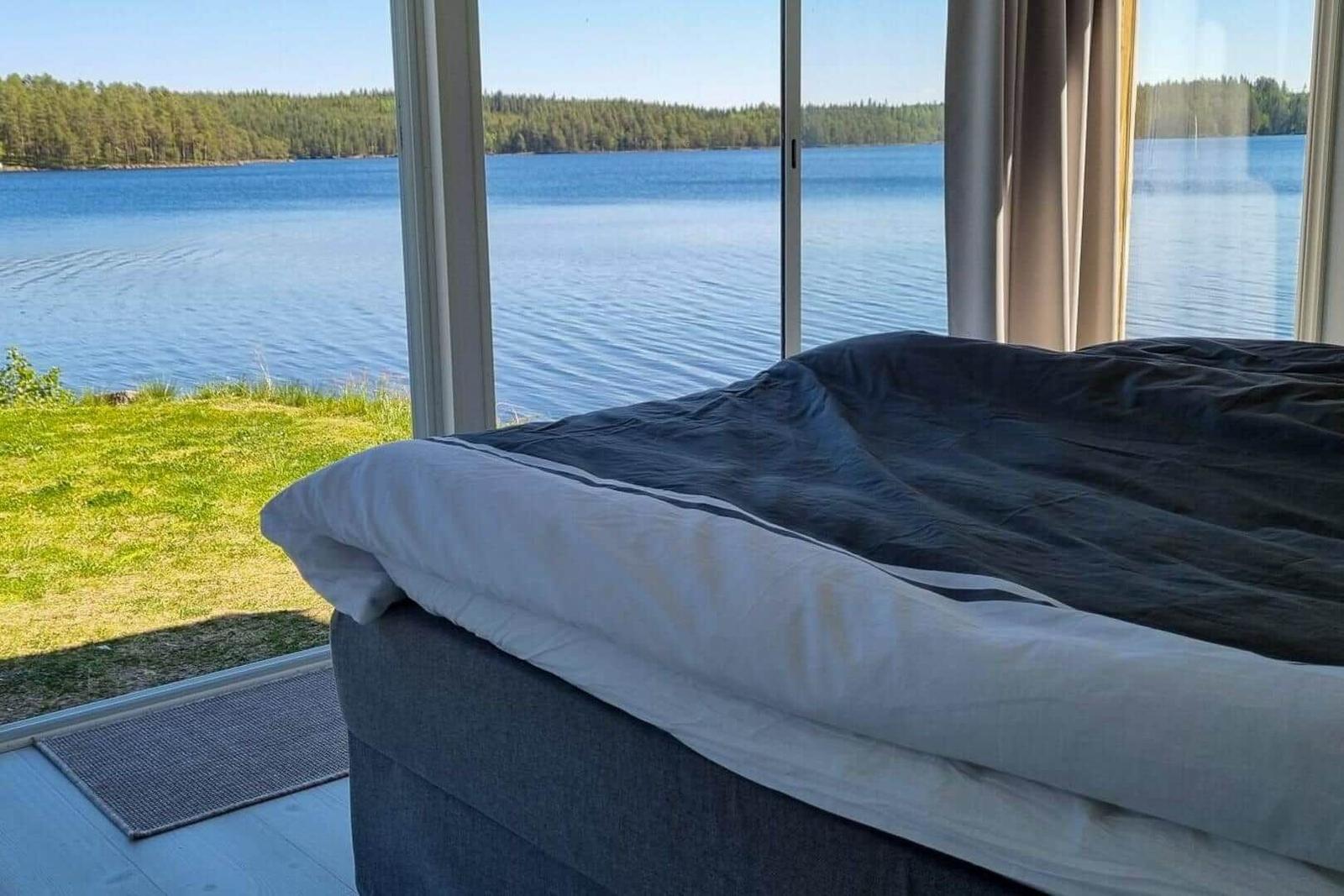 Ein Bett mit Blick auf einen See und Wald.