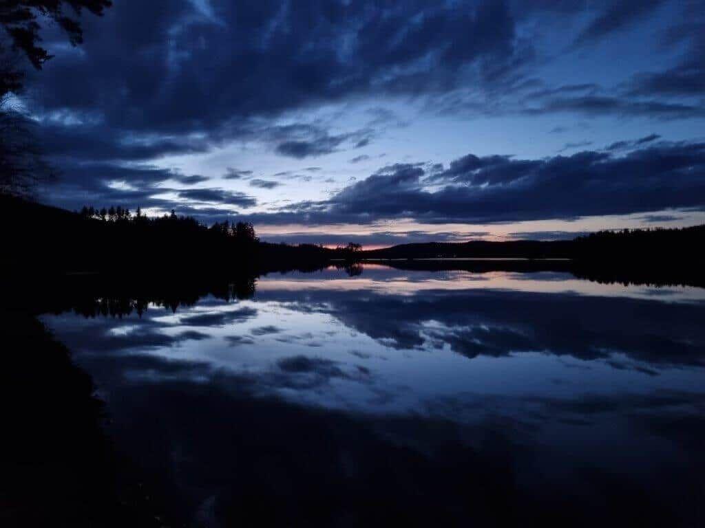 Dämmerung über einem ruhigen See mit Spiegelung des Himmels.
