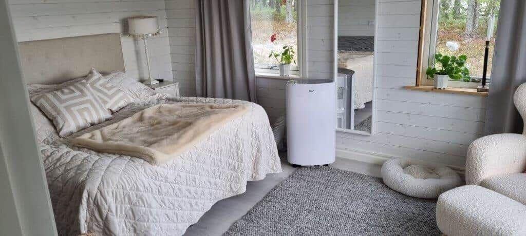 Schlafzimmer mit Bett, Fenster, Spiegel und Sitzgelegenheit.