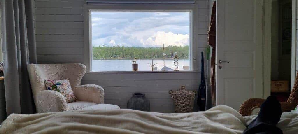 Ein Raum mit Blick auf einen See, ein Sessel und ein Bett sind sichtbar.