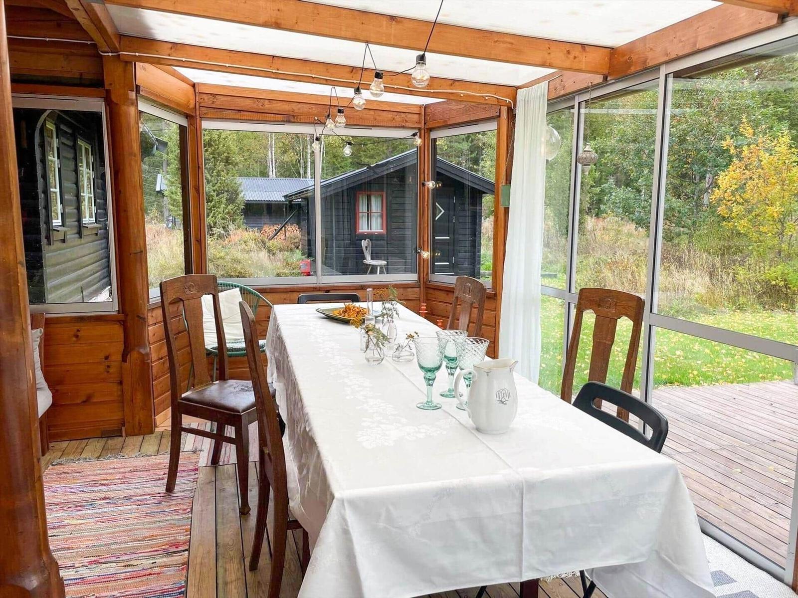 Glasfronten umgeben einen Tisch mit Stühlen und Tischdecke.