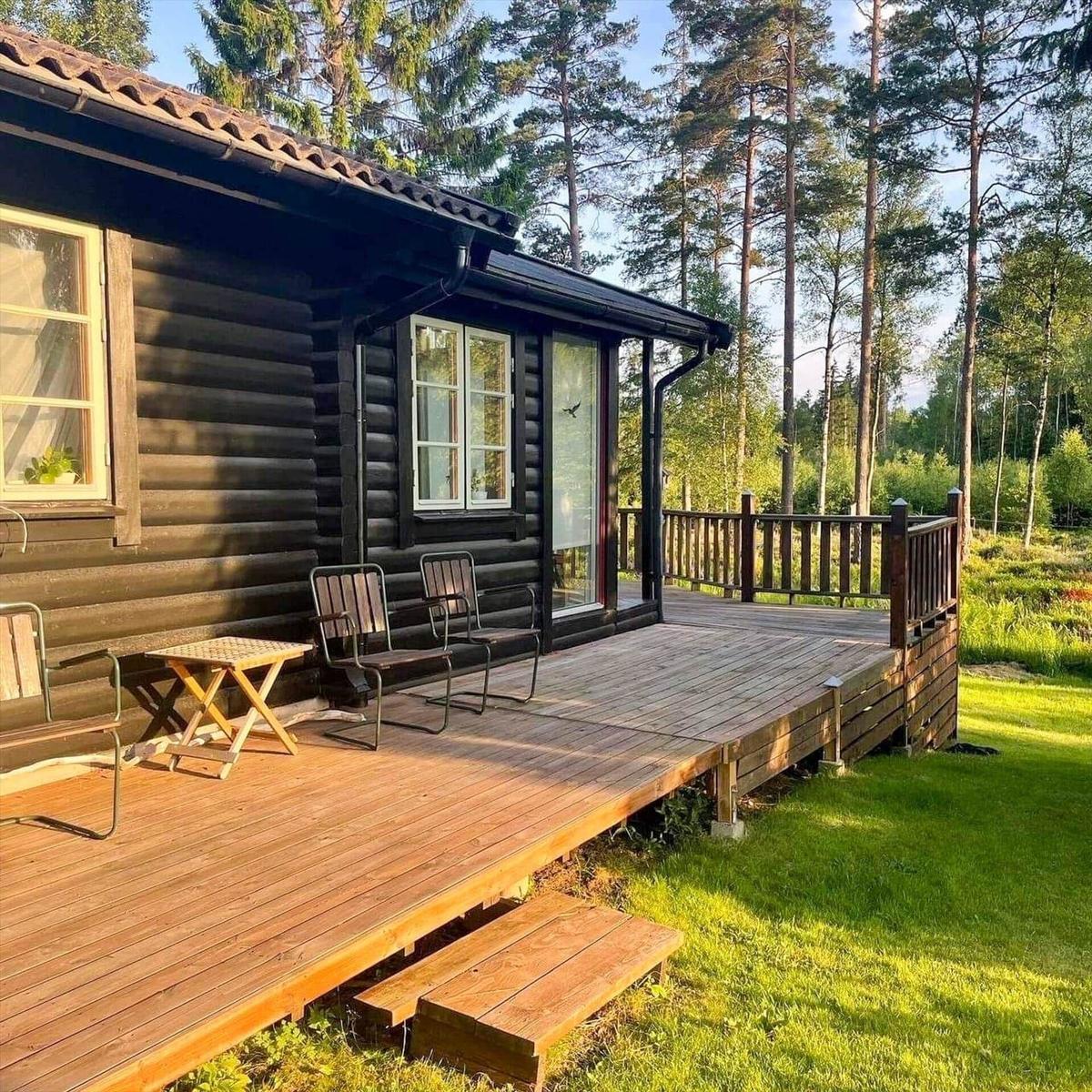 Holzhaus mit Terrasse, Stühlen und Tisch im Wald