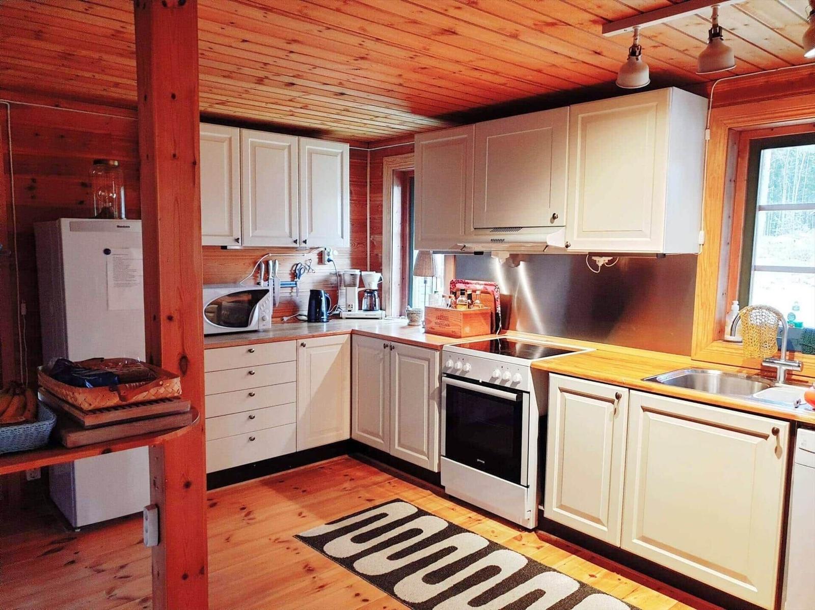 Küche mit weißen Schränken, Holzboden und Fenster zur Außenseite.