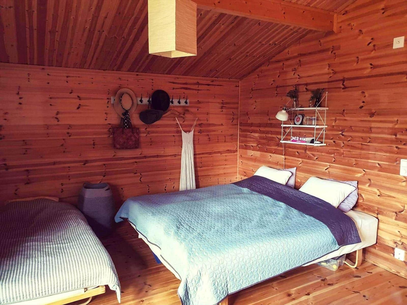Schlafzimmer mit Holzwand, Bett und Kleiderhaken