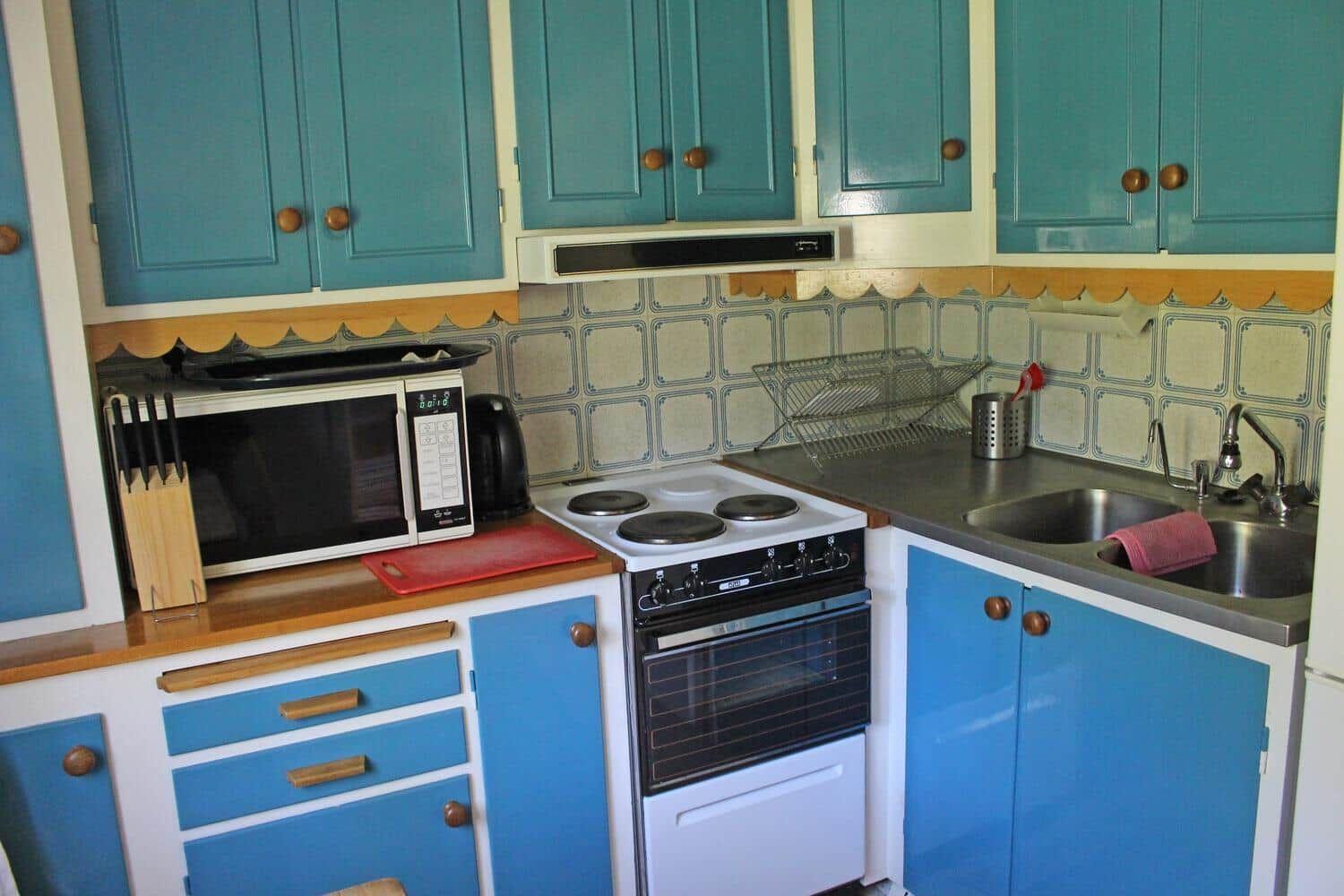 Küche mit blauen Schränken, Herd und Spüle.