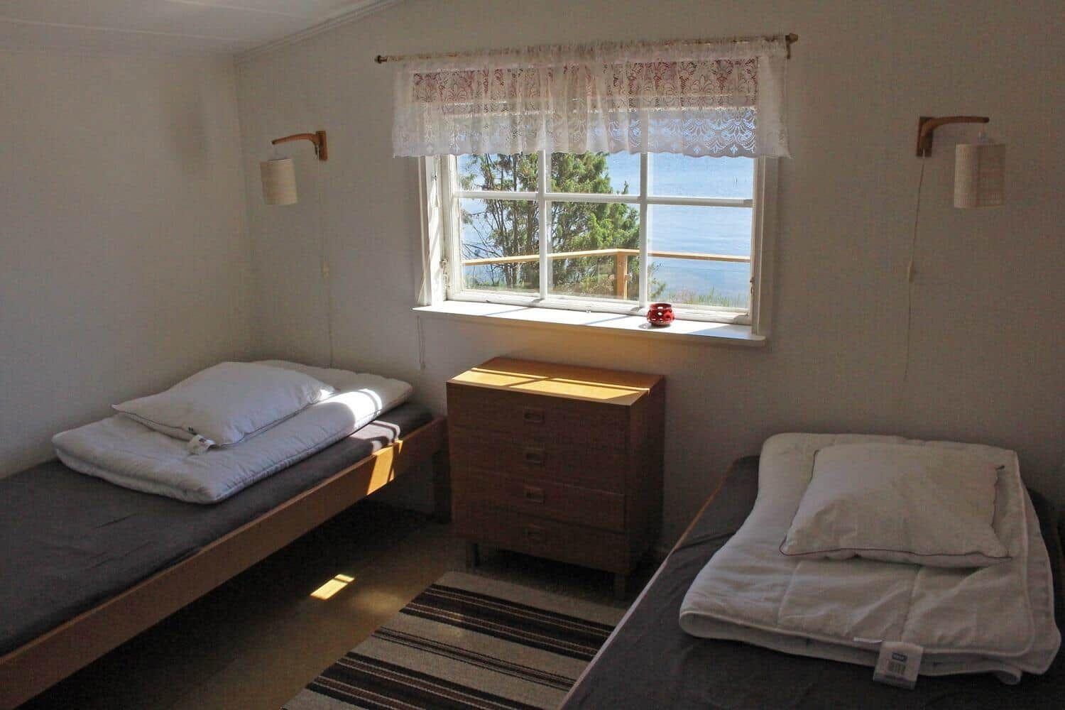 Zwei Betten, Schrank und Fenster mit Meerblick.