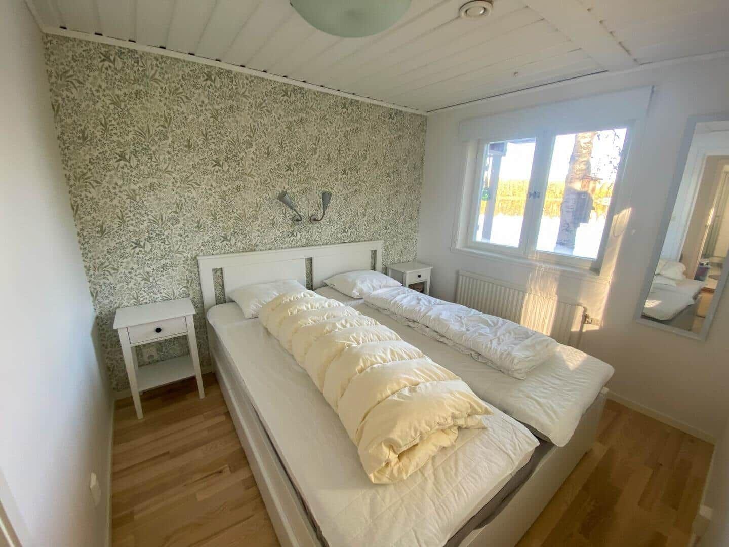 Schlafzimmer mit Doppelbett, Tapete und Fenster.