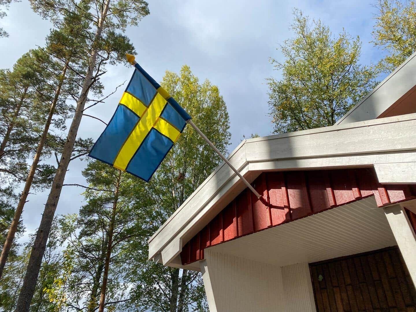 Schwedische Flagge weht vor einem Holzhaus im Wald