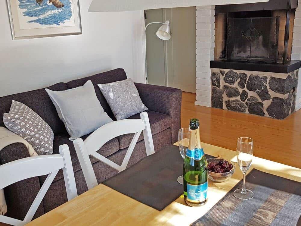 Esstisch mit Flasche und Gläsern vor Sofa und Kamin