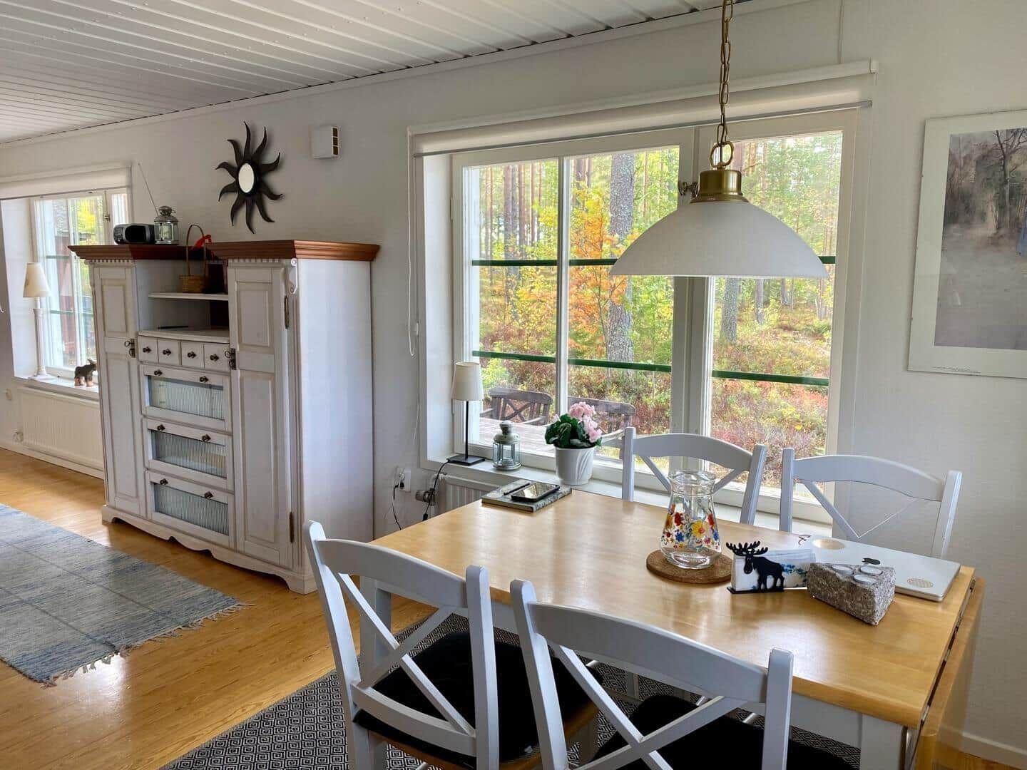 Esszimmer mit Tisch, Stühlen und Blick auf Wald