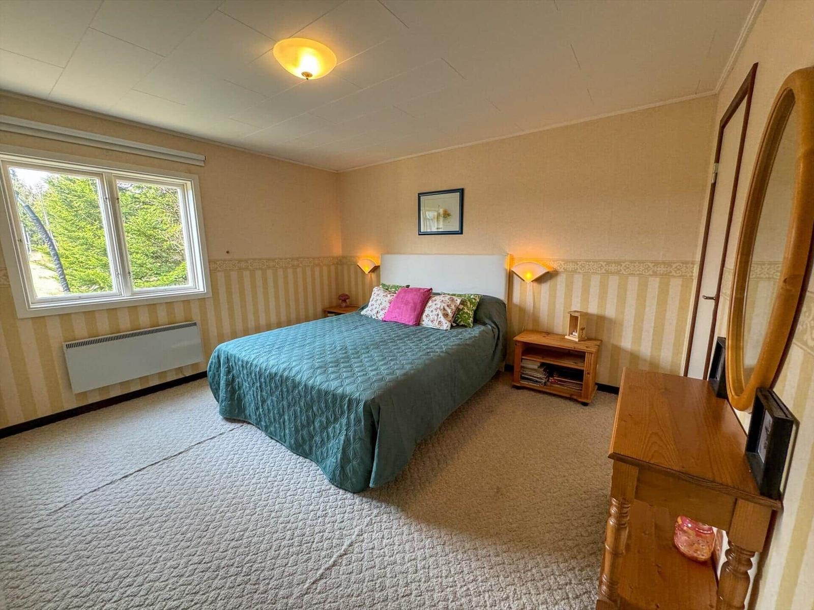 Schlafzimmer mit Bett, Schrank und Fenster zum Blick in den Garten.