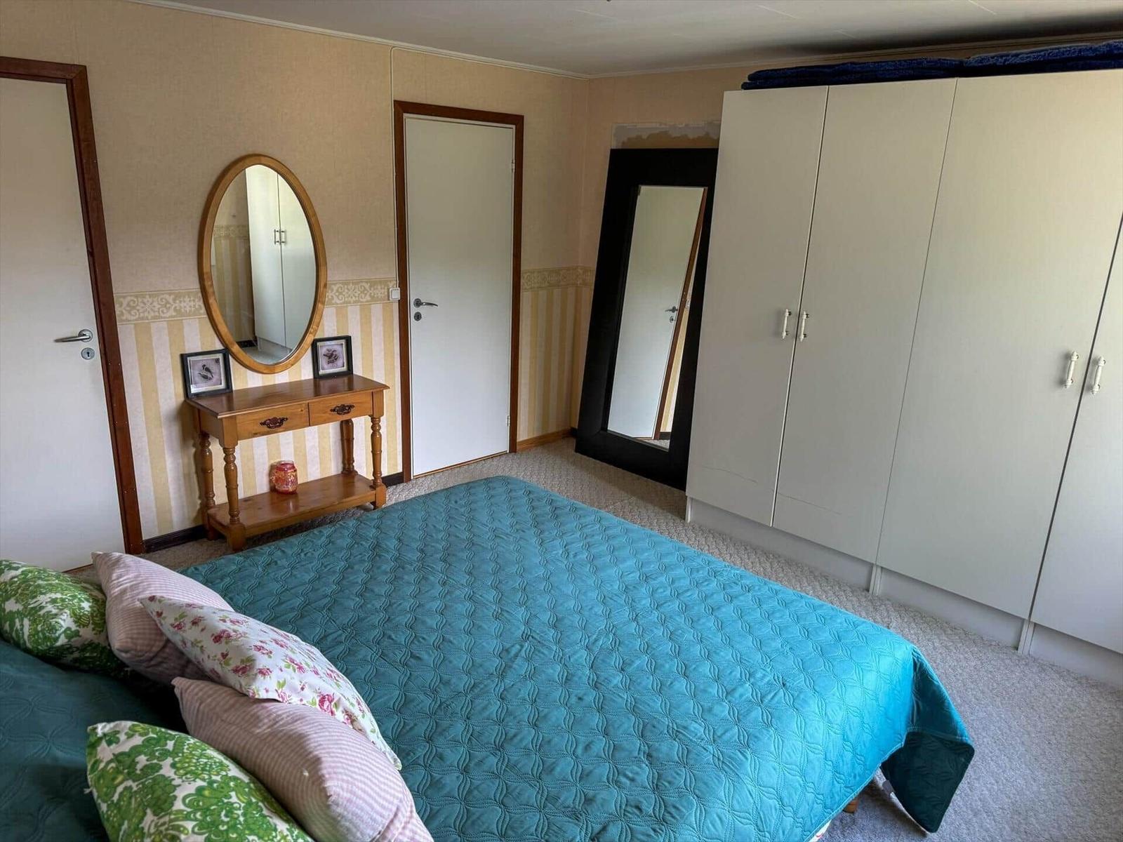 Schlafzimmer mit Bett, Kleiderschrank und Spiegel an der Wand.