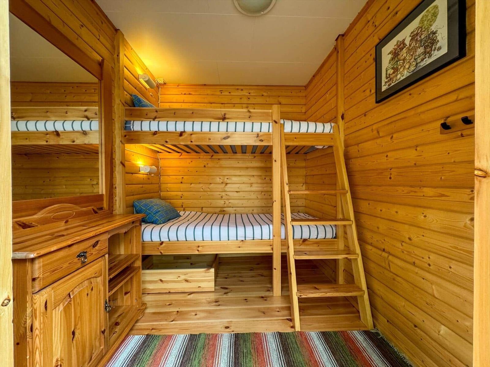 Zimmer mit Holzbett, Schrank und Wandbild.