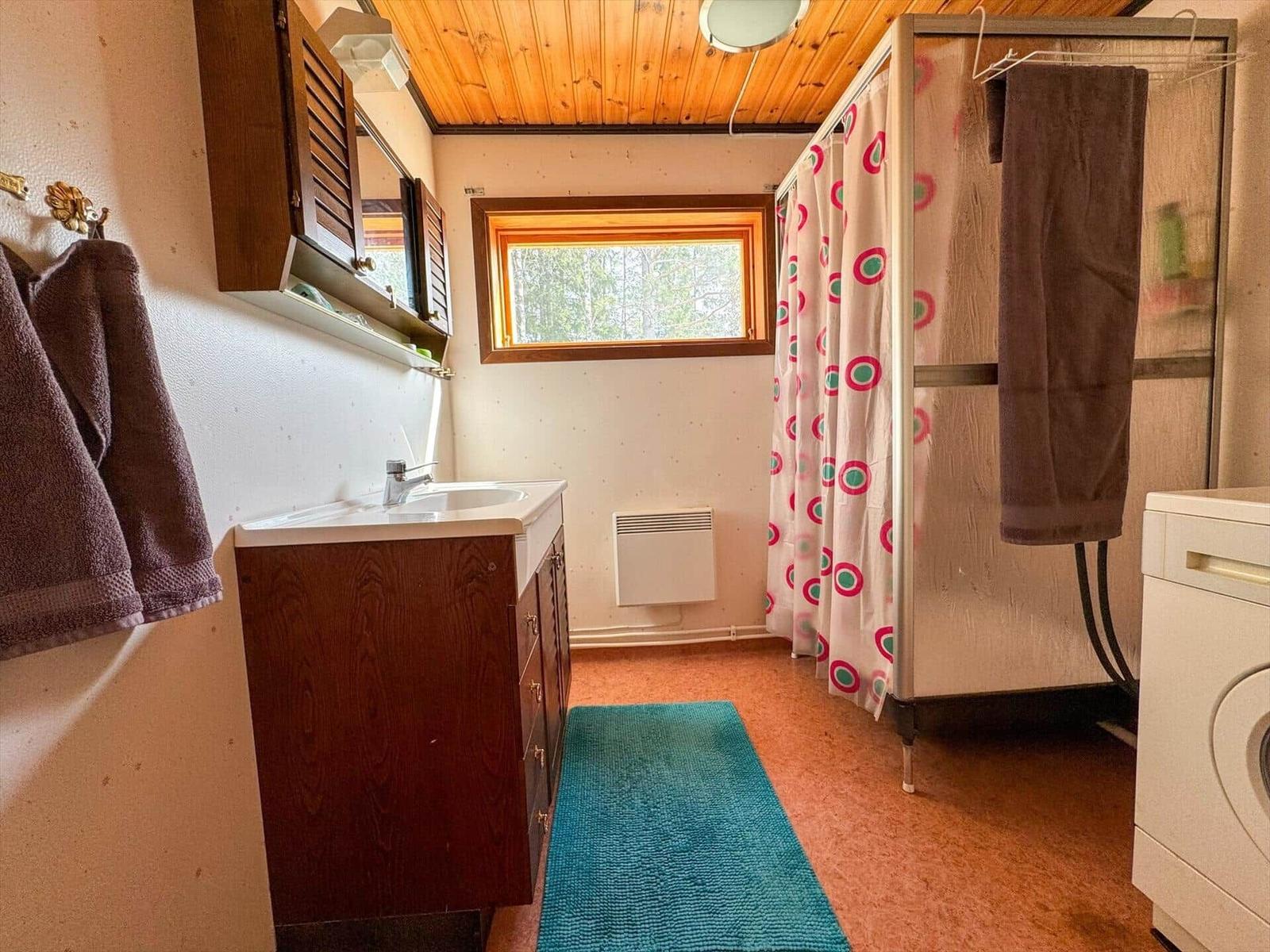 Badezimmer mit Waschbecken, Dusche und Waschmaschine.