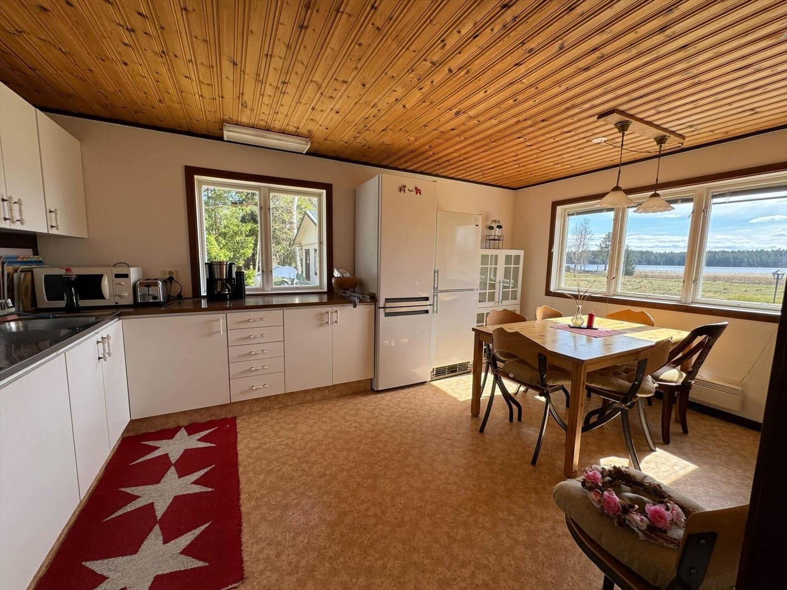Küche und Essbereich mit Holzdecke und Blick auf See.