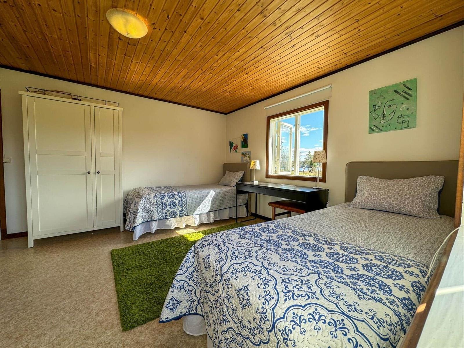 Zimmer mit zwei Betten, Schreibtisch und Fenster mit Blick.