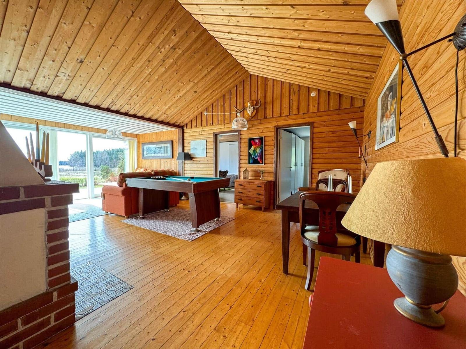 Holzvertäfelte Wohnung mit Billardtisch, Esstisch und Kamin.